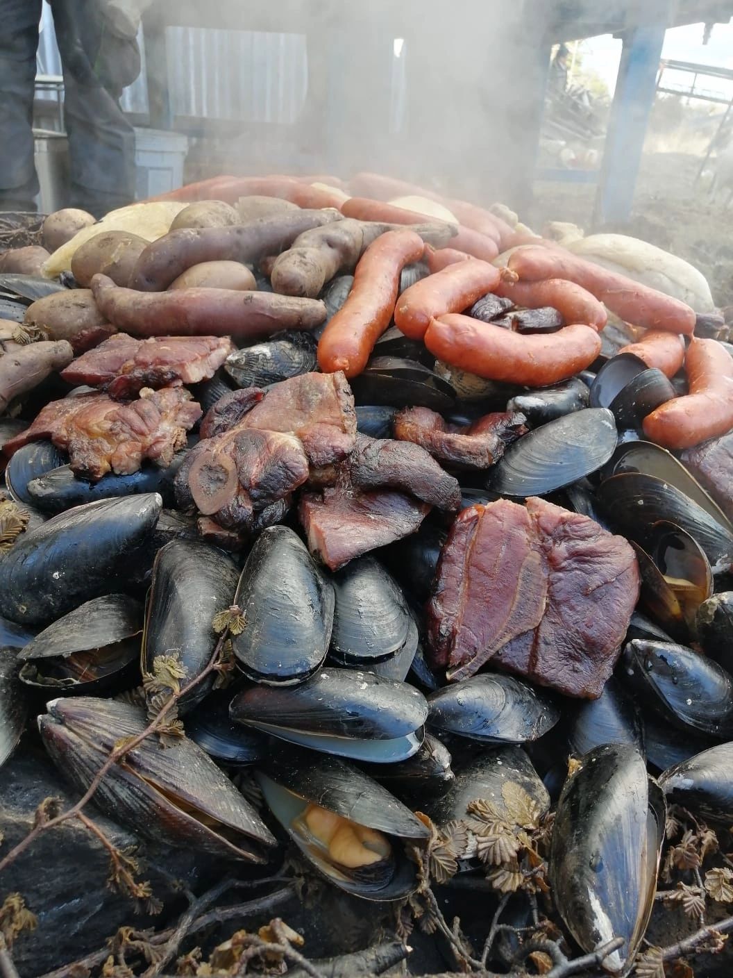 Preparación de un curanto con mariscos y otros alimentos